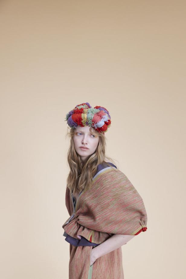 Eine Frau mit blonden Haaren trägt einen bunten Kopfschmuck und ein gemustertes Kleid.