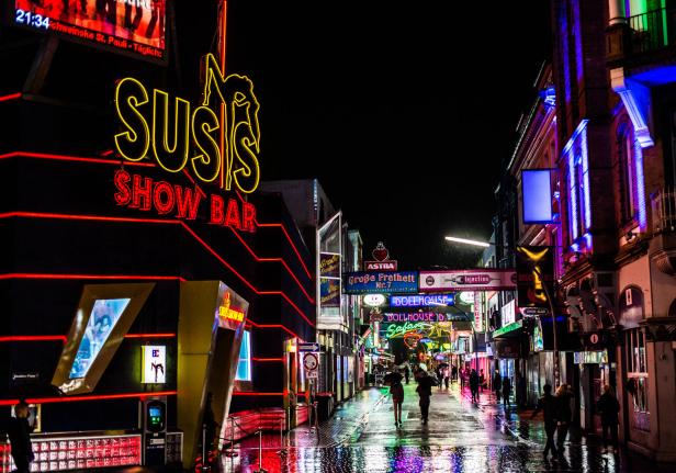 Die Reeperbahn in Hamburg St. Pauli bei Nacht mit Neonreklame und Menschen.
