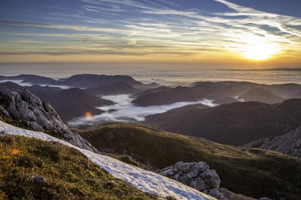 Sonnenaufgang über einer Berglandschaft mit Nebel in den Tälern.
