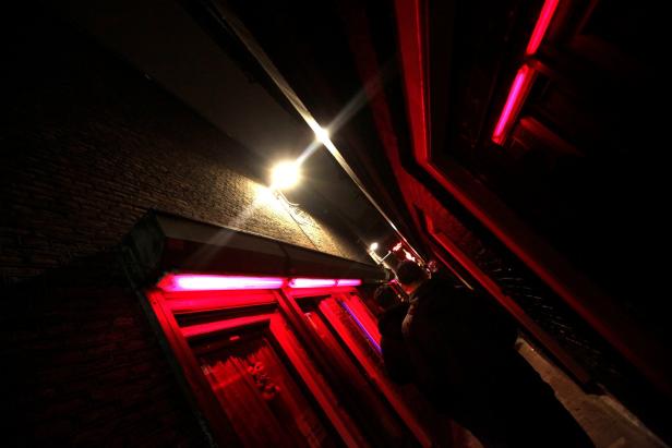Ein dunkler Hauseingang mit roter Beleuchtung und einer Person im Schatten.