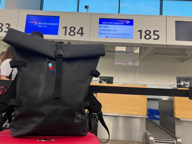 Ein schwarzer Rucksack steht vor einem British Airways Check-in-Schalter.