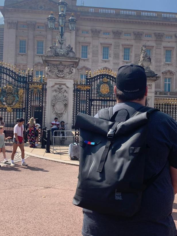 Ein Mann mit Rucksack vor dem Buckingham Palace in London.
