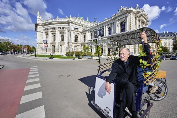 Ein Mann sitzt in einer Rikscha vor dem Burgtheater in Wien.
