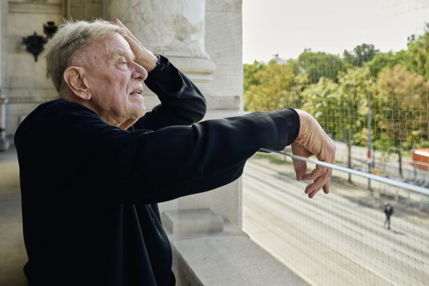 Ein älterer Mann blickt von einem Balkon auf die Straße.