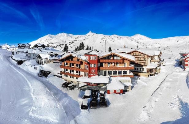 Das Hotel Kristall liegt in einer verschneiten Winterlandschaft in den Bergen.