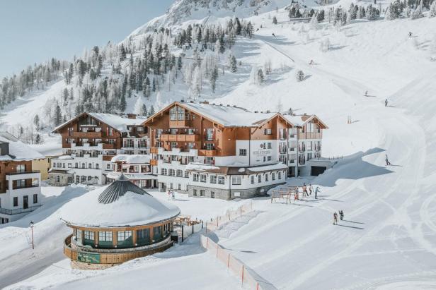 Das Hotel Schneider****Superior liegt in einer verschneiten Winterlandschaft mit Skipiste.