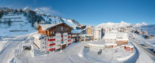 Das Hotel Enzian & Zirbenspa in einer verschneiten Winterlandschaft.