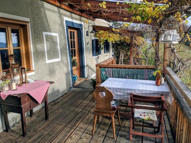 Ein gedeckter Tisch und Stühle stehen auf einer hölzernen Veranda.