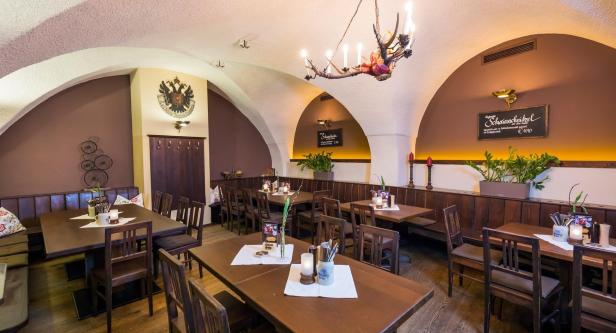 Innenansicht eines traditionellen bayerischen Restaurants mit Holztischen und Gewölbedecke.