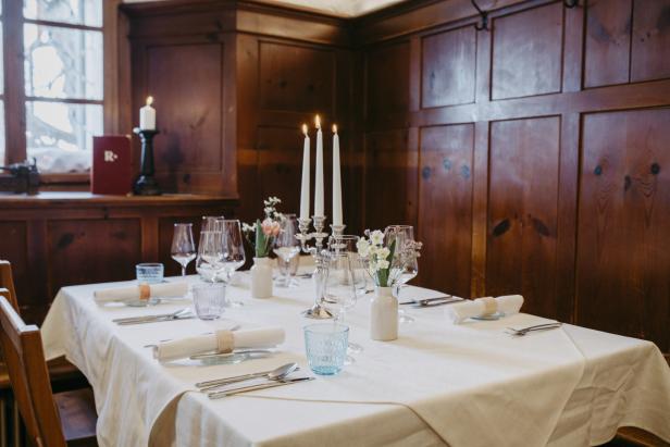 Ein festlich gedeckter Tisch mit weißen Stoffservietten und Blumenarrangements in einem Restaurant.