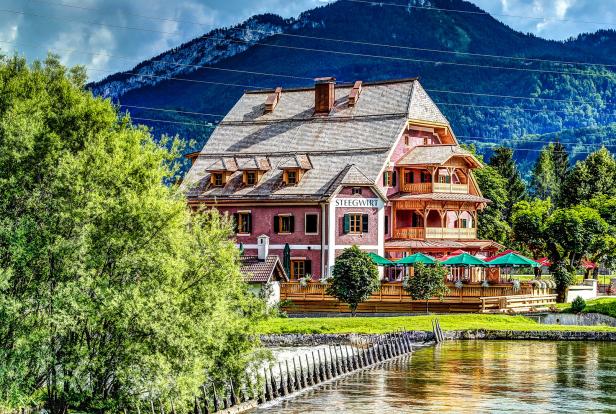 Das Hotel Steegwirt liegt malerisch an einem Fluss mit einem Berg im Hintergrund.