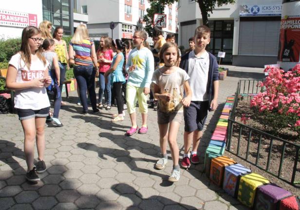 Eine Gruppe von Kindern geht auf einem Bürgersteig entlang.