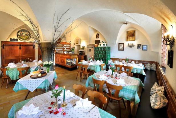 Ein Speisesaal mit gedeckten Tischen in einem Restaurant mit Gewölbedecke.
