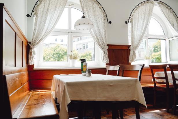 Ein Tisch mit weißer Tischdecke in einem hellen Restaurant mit Holzvertäfelung.