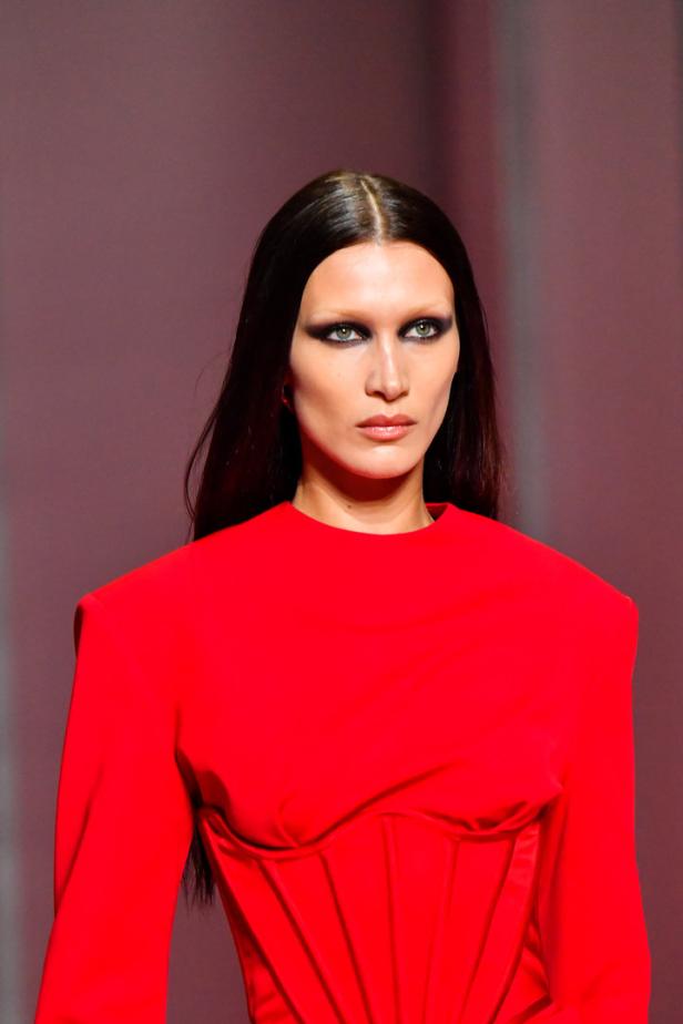 Bella Hadid präsentiert ein rotes Kleid mit Korsett auf dem Laufsteg.