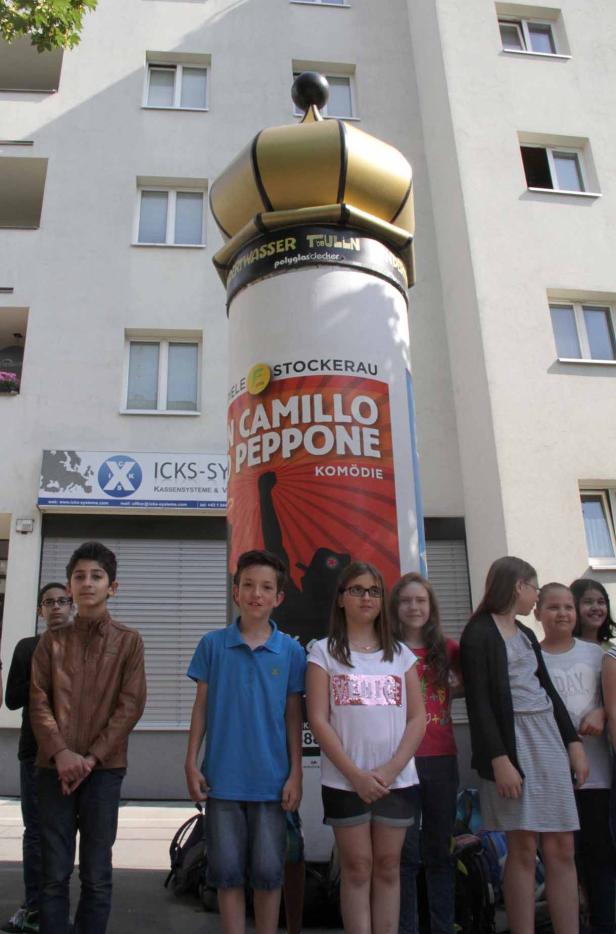 Eine Gruppe von Kindern steht vor einer Litfaßsäule mit der Aufschrift „Camillo & Peppone“.