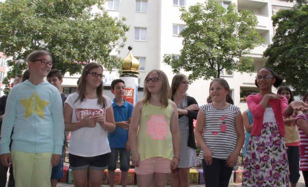 Eine Gruppe von Kindern steht im Freien vor einem Gebäude.