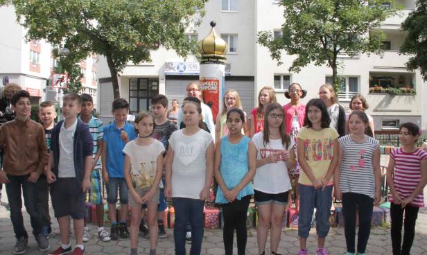 Eine Gruppe von Jungen und Mädchen steht im Freien vor einem Gebäude.