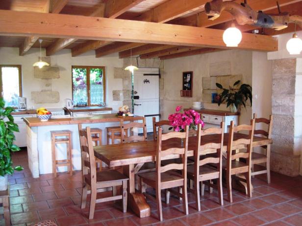 Ein Esszimmer mit Holztisch, Stühlen und rustikalen Holzbalken an der Decke.