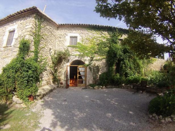 Ein mit Efeu bewachsenes Steinhaus mit einer offenen Holztür.