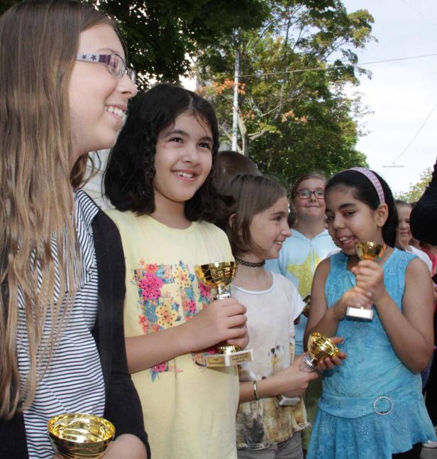 Eine Gruppe junger Mädchen hält stolz ihre goldenen Trophäen in den Händen.