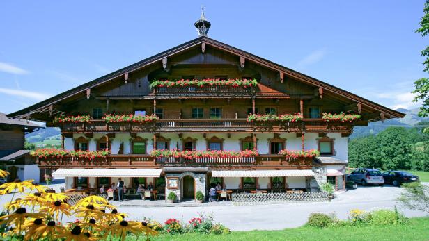 Ein traditionelles bayerisches Haus mit blumengeschmückten Balkonen und einem Restaurant im Erdgeschoss.