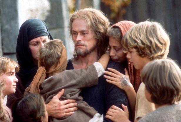 Willem Dafoe als Jesus umgeben von Frauen und Kindern.
