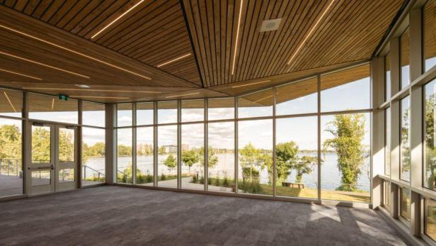 Ein leerer Raum mit großen Fenstern und Blick auf einen See.