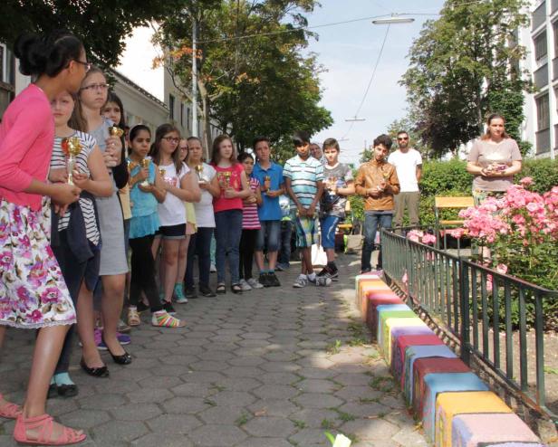 Eine Gruppe Kinder steht mit kleinen goldenen Pokalen in einer Reihe.