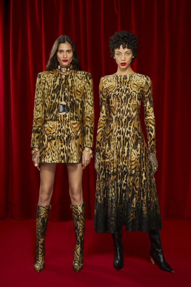 Zwei Models präsentieren Kleidung mit Leopardenmuster vor einem roten Vorhang.