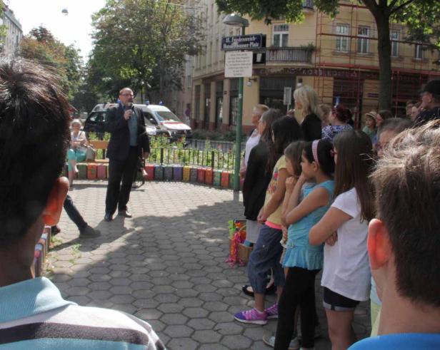 Ein Mann spricht vor einer Gruppe von Menschen auf dem Friedensreich-Hundertwasser-Platz.