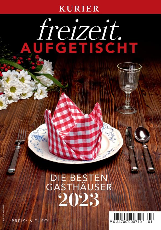 Ein gedeckter Tisch mit karierter Serviette und dem Titel „Die besten Gasthäuser 2023“.