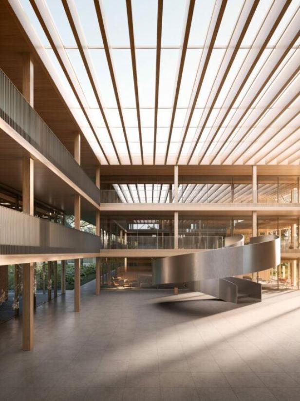 Das Atrium eines modernen Bürogebäudes mit einer Wendeltreppe und viel Tageslicht.