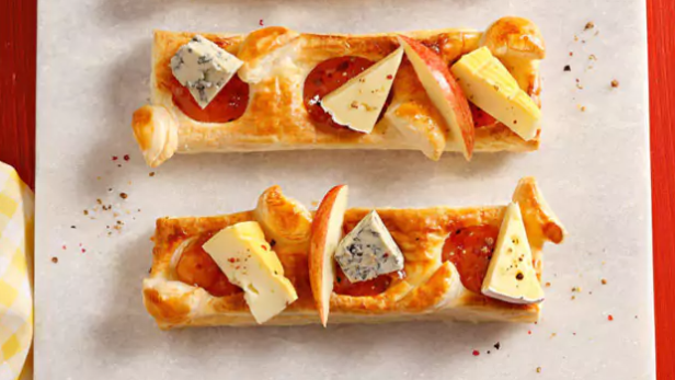 Blätterteig-Fingerfood belegt mit Käse, Aprikosenmarmelade und Apfelspalten.