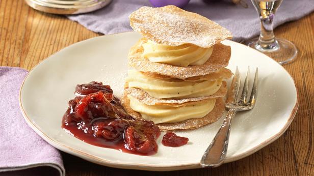 Ein Vanille-Millefeuille mit Pflaumenkompott auf einem Teller.