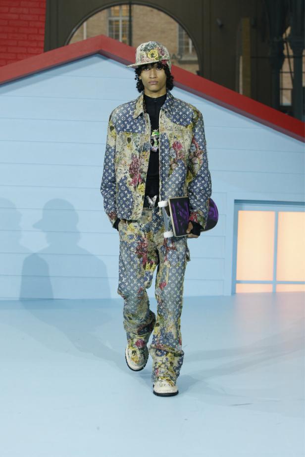 Ein Mann in einem floralen Louis Vuitton Anzug mit Skateboard auf einem Laufsteg.