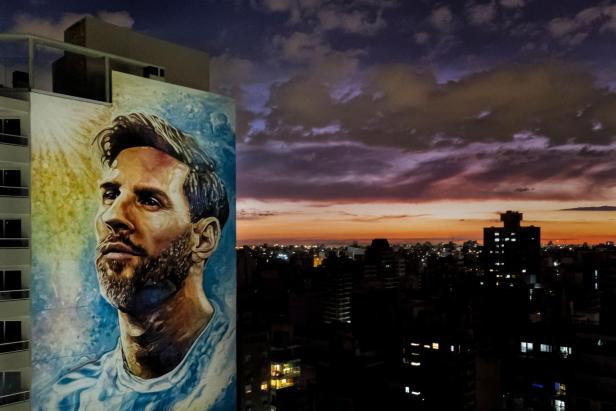 Ein Wandgemälde von Lionel Messi vor einem Sonnenuntergang in Rosario, Argentinien.