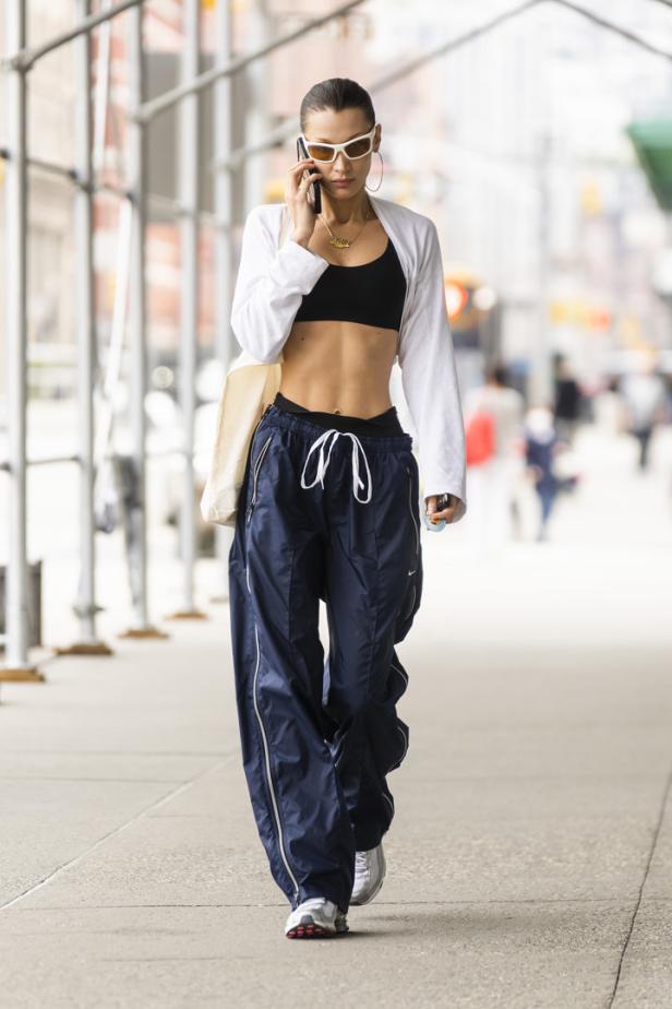Bella Hadid telefoniert auf der Straße in Sportkleidung.