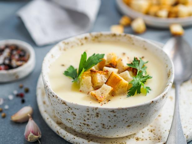 Eine Schüssel cremige Suppe, garniert mit Croutons und Petersilie.
