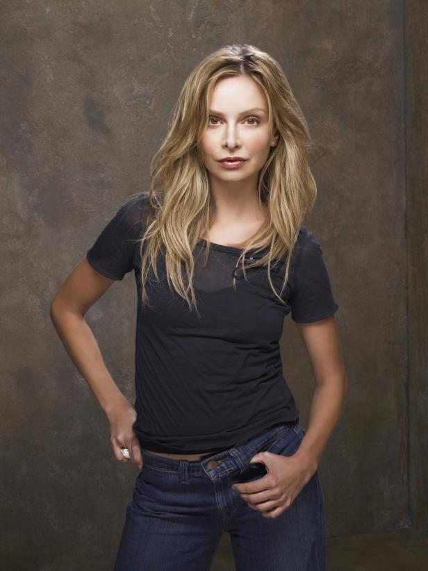Eine Frau mit blonden Haaren posiert in einem schwarzen T-Shirt und Jeans.