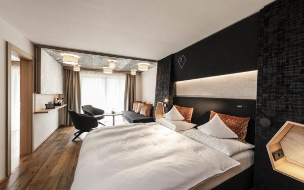 Ein modernes Hotelzimmer mit einem großen Bett, einer Sitzecke und Holzboden.