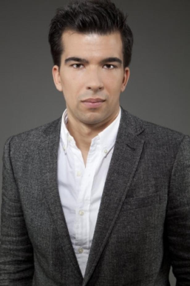 David Haunold, Gründer und CEO von Holivia.com (c: holivia) Ein Mann mit dunklen Haaren trägt ein graues Jackett und ein weißes Hemd.