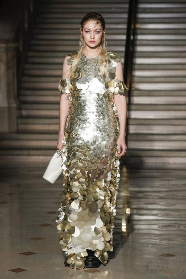 Gigi Hadid trägt ein goldenes Paillettenkleid auf einer Treppe.