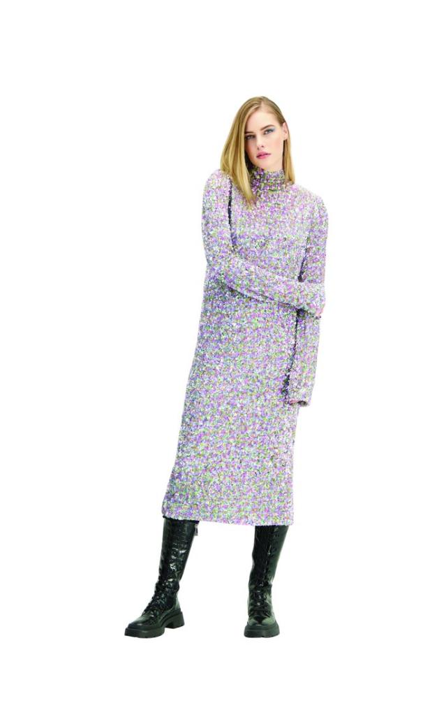 Eine Frau trägt ein lila, paillettenbesetztes Kleid mit Rollkragen und schwarze Stiefel.