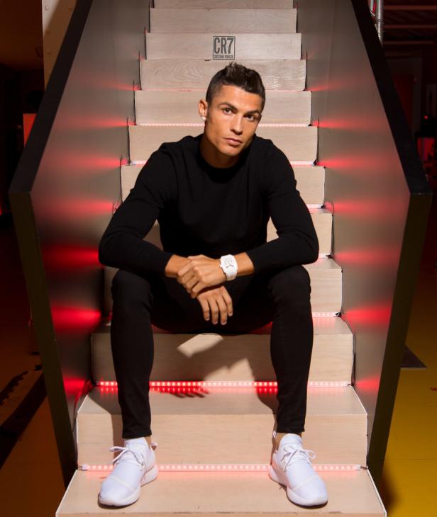 Cristiano Ronaldo sitzt auf einer Treppe mit roter Beleuchtung.
