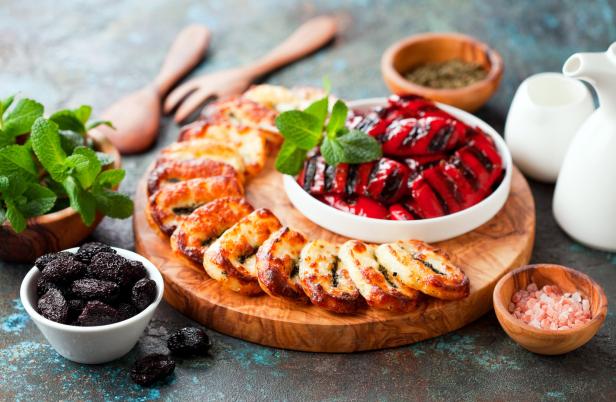 Gegrillter Halloumi, Paprika und Pflaumen auf einem Holzbrett angerichtet.