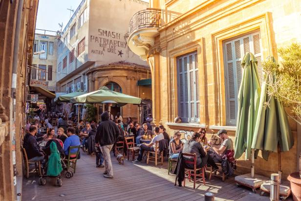 Menschen sitzen in einem Straßencafé in einer sonnigen Stadt.