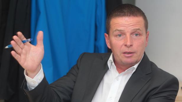 Ein Mann im Anzug gestikuliert mit einem Stift in der Hand.