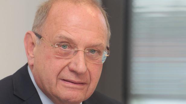 Porträt eines älteren Mannes mit Brille und Anzug.