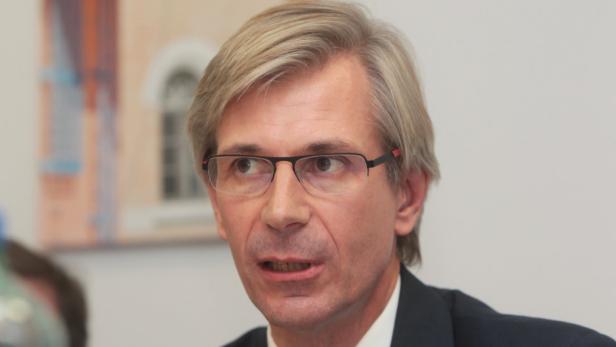 Ein Mann mit blonden Haaren und Brille spricht.